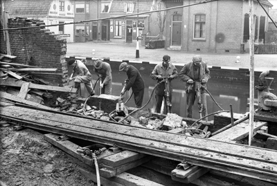 818012 Afbeelding van enkele arbeiders met pneumatische hamers tijdens het slopen van een muur van de N.V. Jutfaase ...